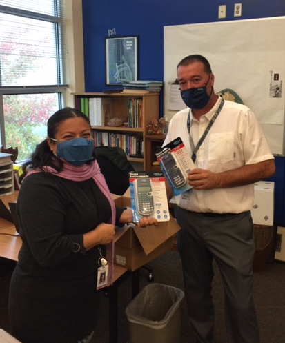 Two staff members take a picture holding calculators.